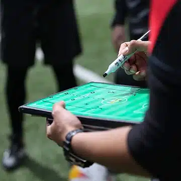 Close-up of a coach marking positional detail on a tactics board