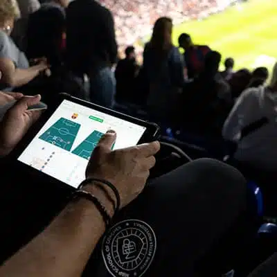 A coach analysing a match on a tablet in a stadium
