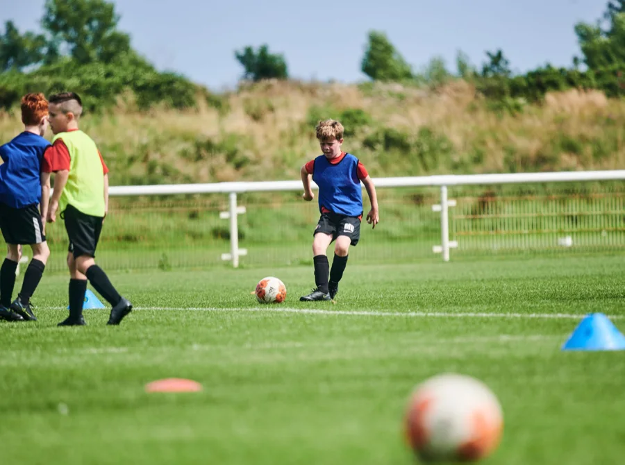 A young player dribbling in a training match